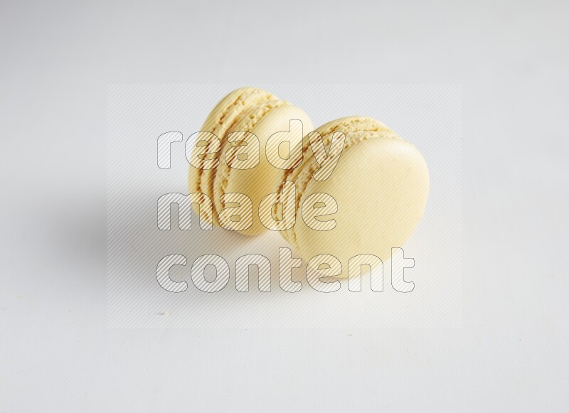 45º Shot of two Yellow Vanilla macarons on white background