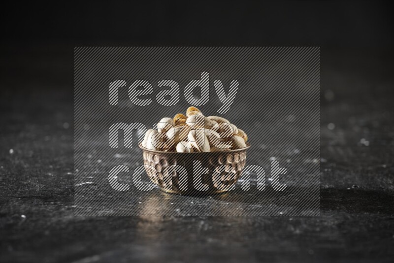 Nuts in a metal bowl in a dark setup