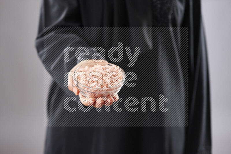 Woman in abaya holding different kinds of spices in different positions