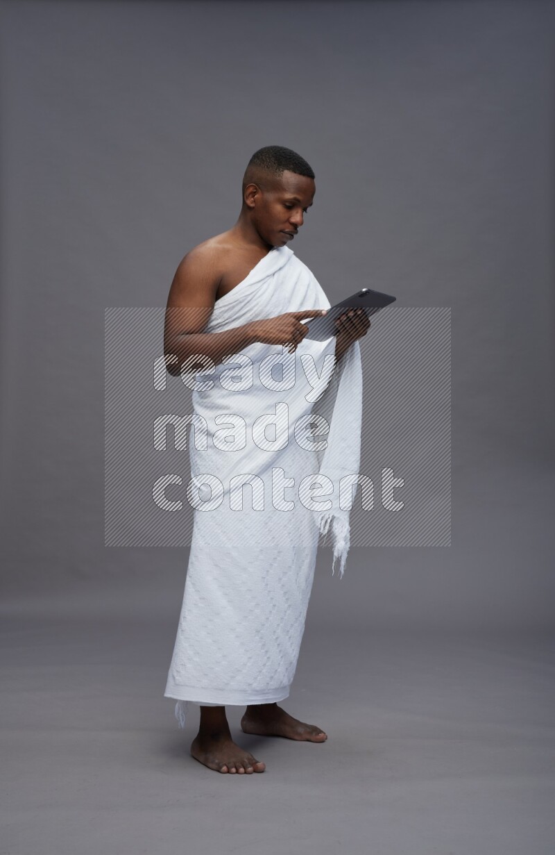 A man wearing Ehram Standing working on tablet on gray background