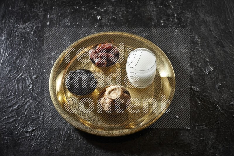 Dried fruits in metal bowls with sobya on a tray in dark setup