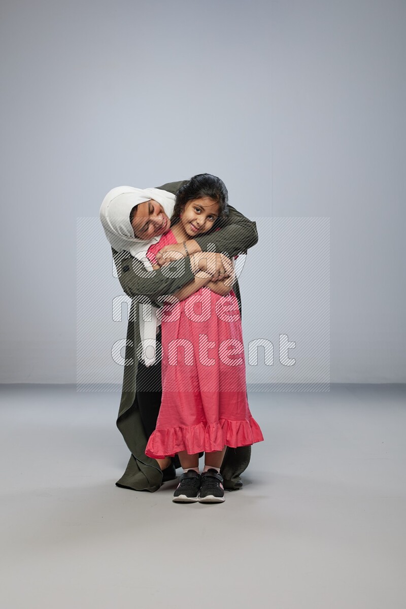 A girl and her mother interacting with the camera on gray background