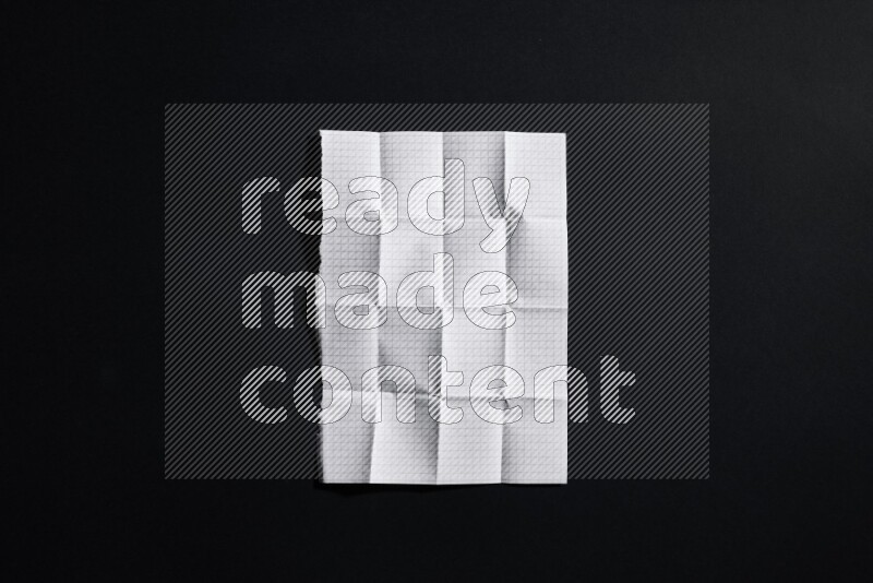 Folded notebook sheet on black background