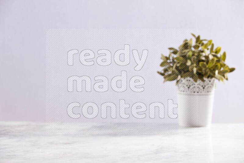 Artificial plant in white decorative pot on grey marble background