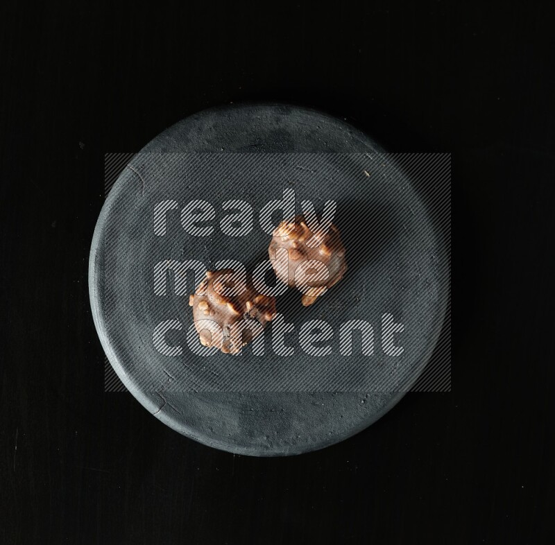 Assorted desserts in a black pottery plate on black background
