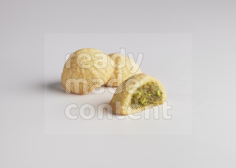 Three Pieces of Maamoul filled with pistachio paste  one of them is cut direct on white background