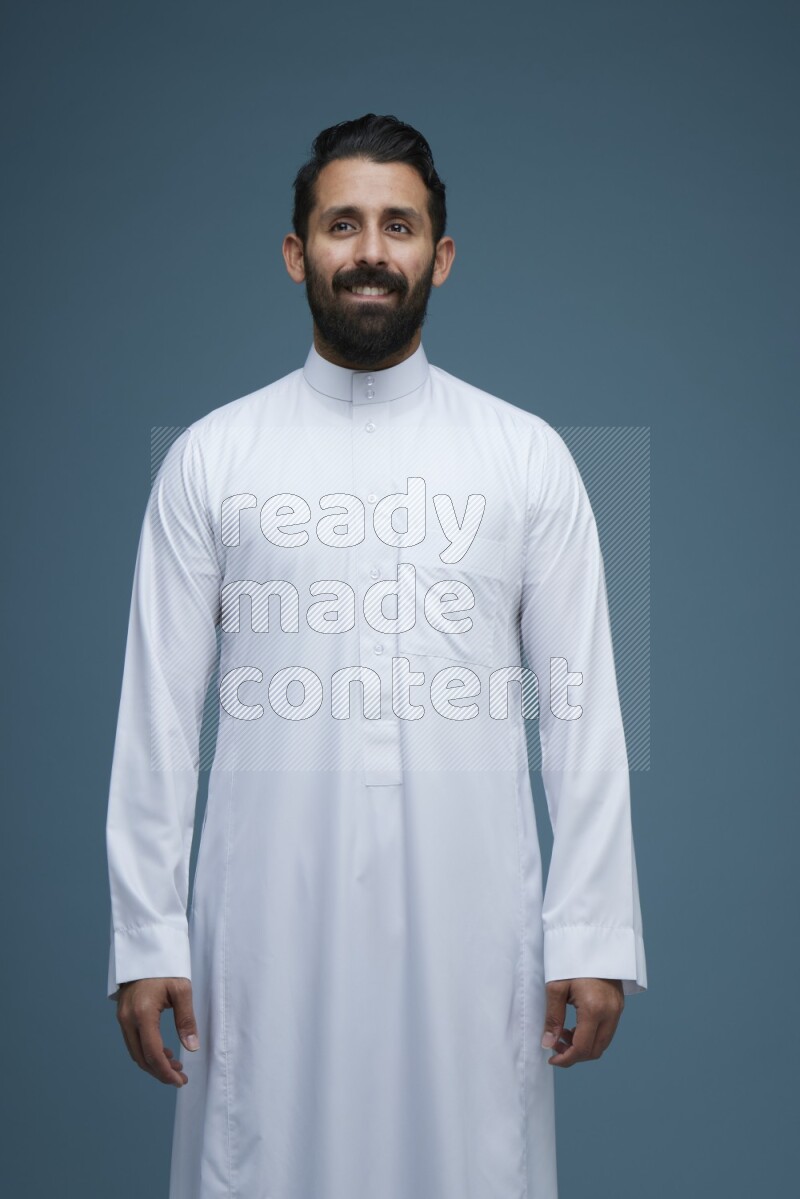 A man posing in a blue background wearing Saudi Thob