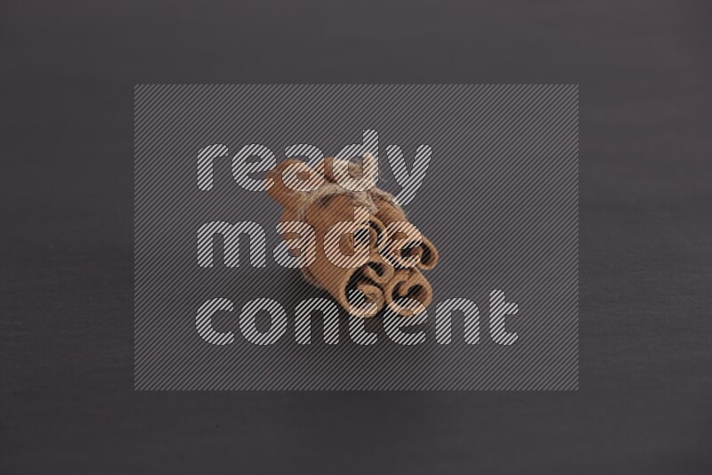 4 أعواد من القرفة مربوطة علي خلفية سوداء