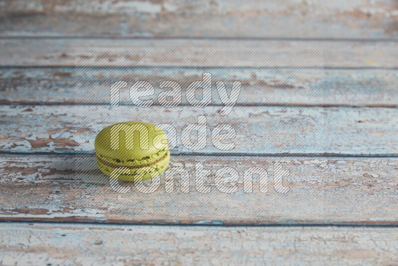 45º Shot of Green Pistachio macaron on light blue wooden background