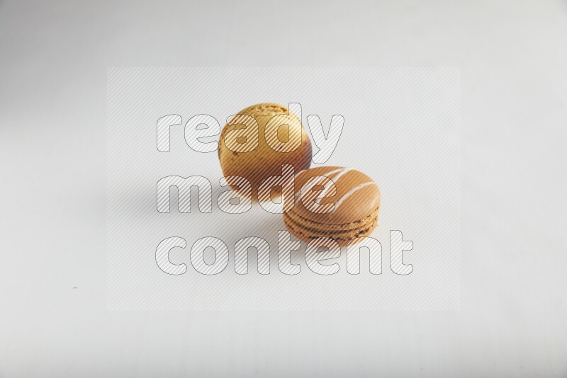 45º Shot of of two assorted Brown Irish Cream, and Yellow Crème Brulée macarons on white background