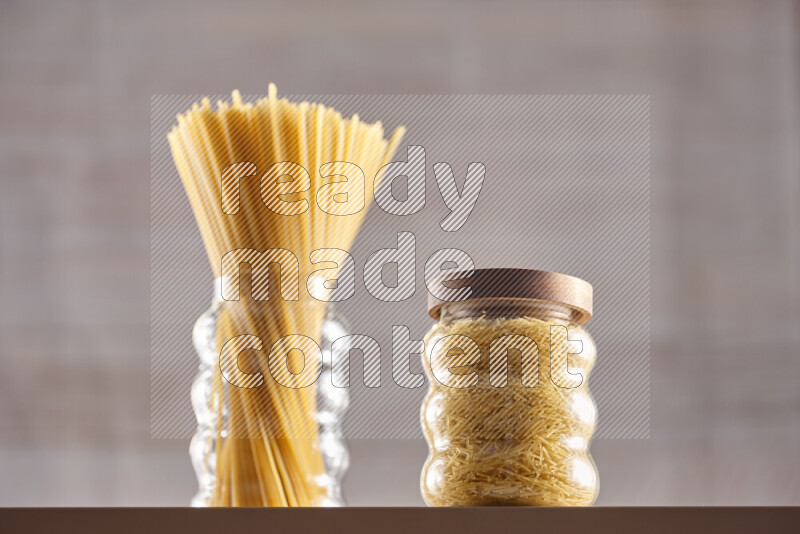Raw pasta in glass jars on beige background