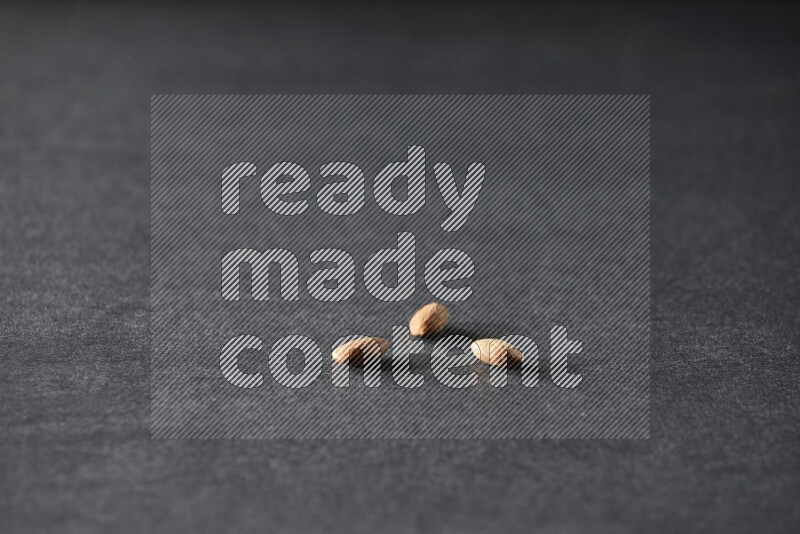 3 peeled almonds on a black background in different angles