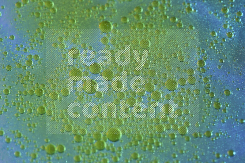 لقطات مقربة لقطرات ألوان مائية صفراء على سطح الزيت على خلفية زرقاء