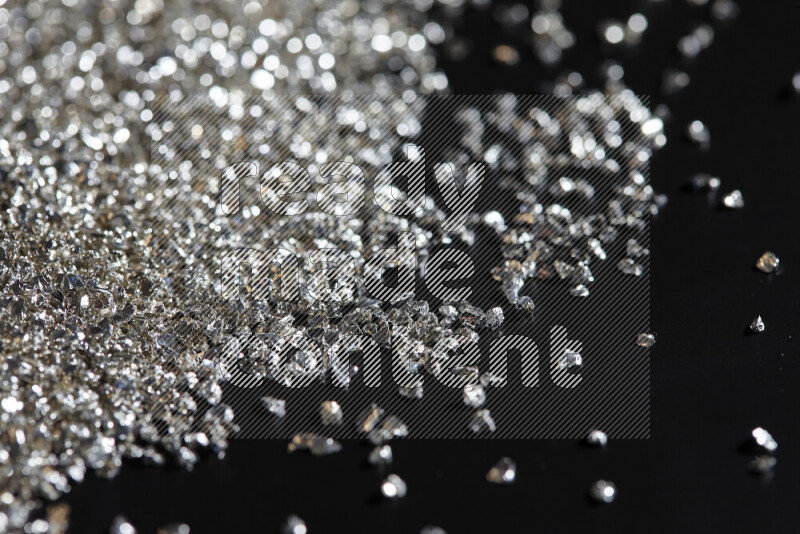 Silver shimmering fragments of glass scattered on a black background