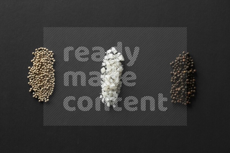 White pepper, salt and black pepper lined on a black background
