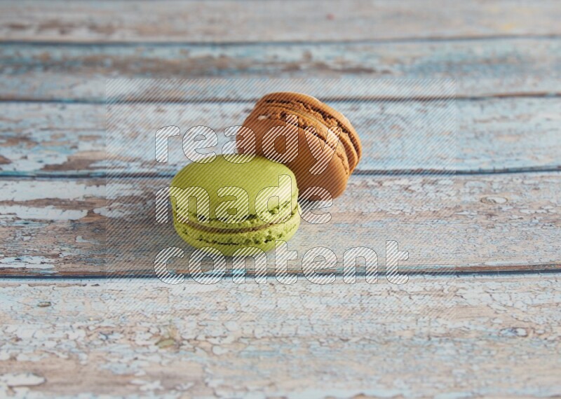 45º Shot of of two assorted Brown Irish Cream, and Green Pistachio macarons  on light blue background