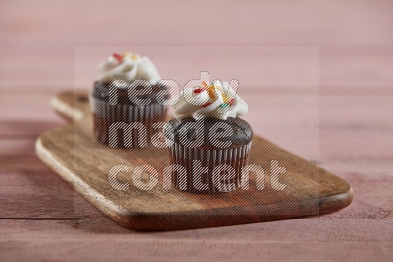 Chocolate mini cupcake topped with cream on a wooden board