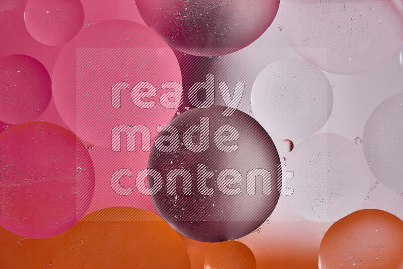 Close-ups of abstract oil bubbles on water surface in shades of white, orange and pink