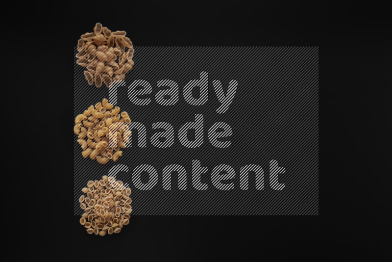 Different pasta types in 3 bunches on black background