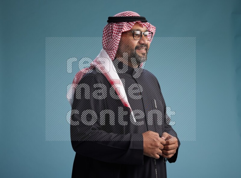 Saudi Man with shimag Standing Interacting with the camera on blue background