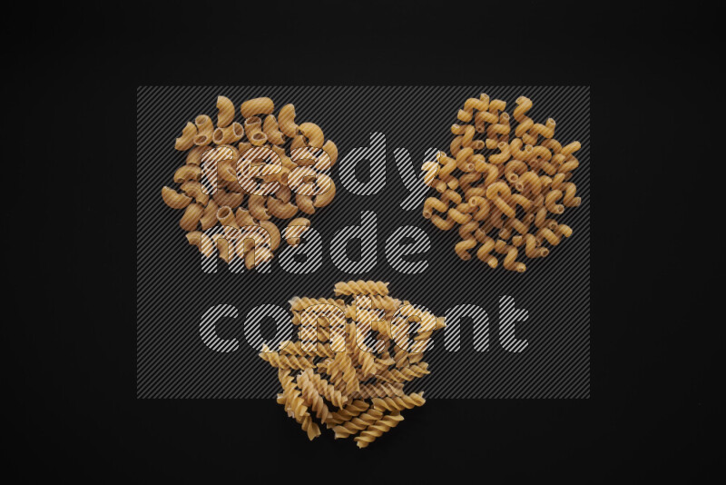 Different pasta types in bunches on black background