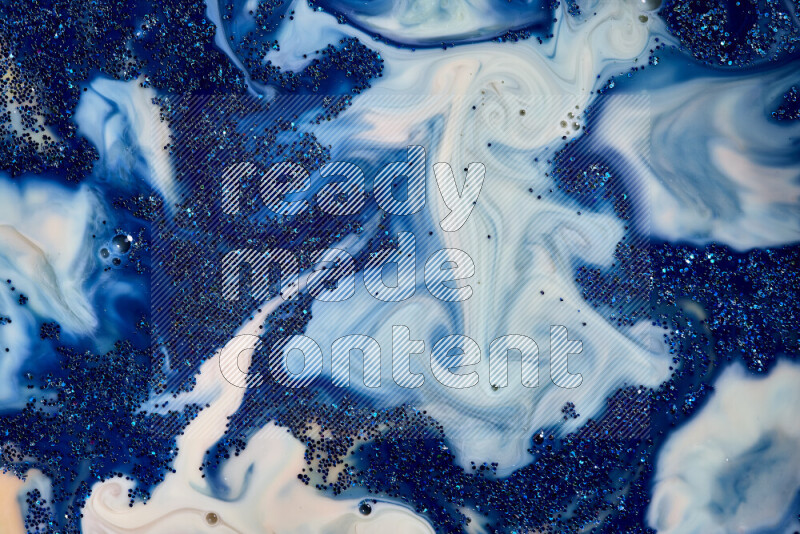 A close-up of sparkling blue glitter scattered on swirling blue and white background