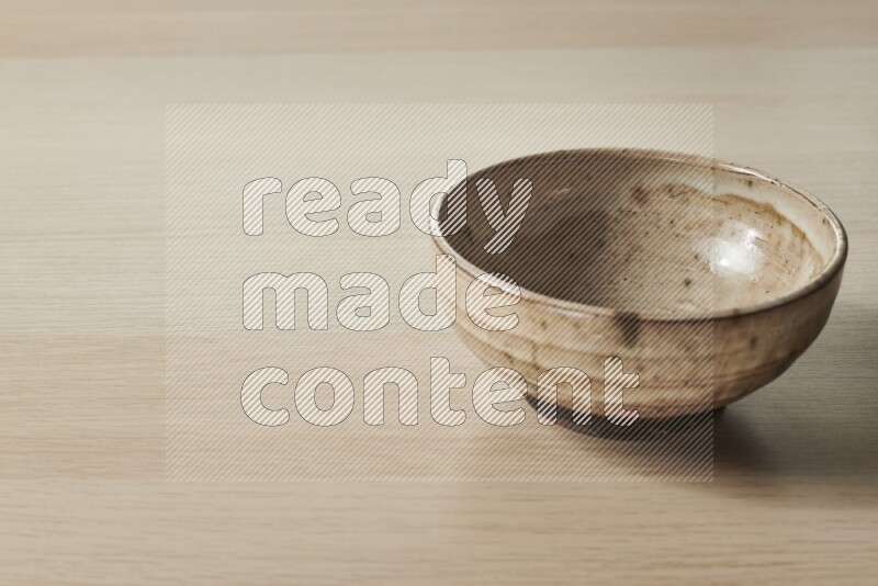 A beige pottery bowl on light wooden background