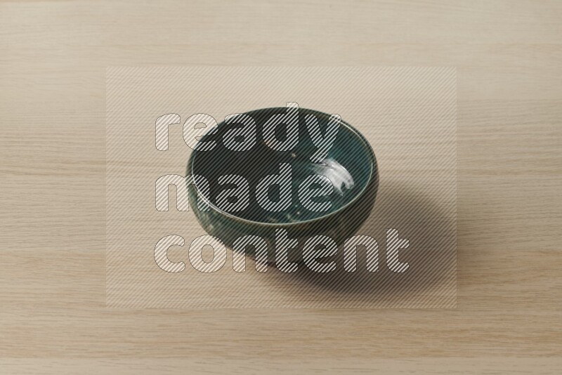 A dark green pottery bowl on light wooden background