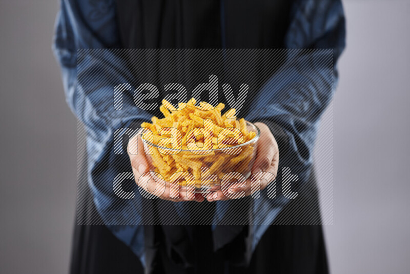 Woman in abaya holding different kinds of snacks in different positions