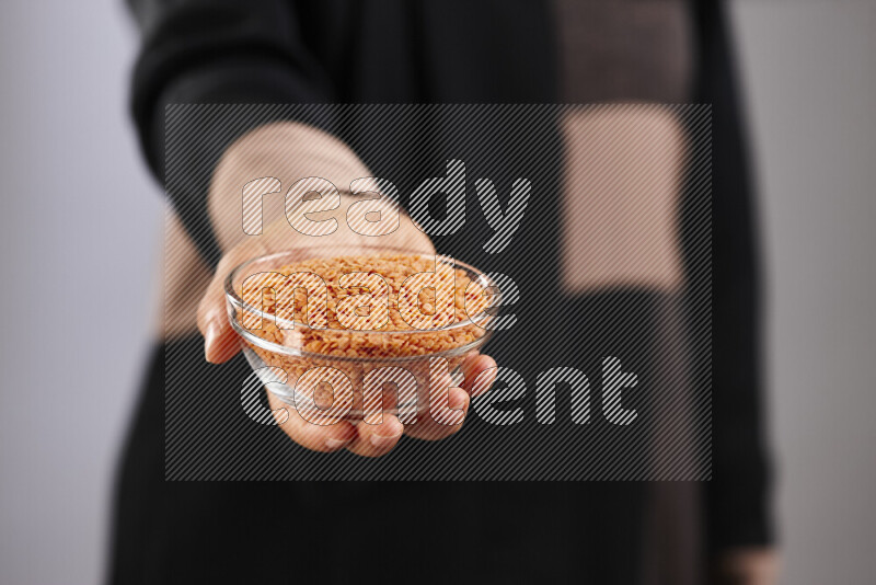 Woman in abaya holding different kinds of legumes in different positions