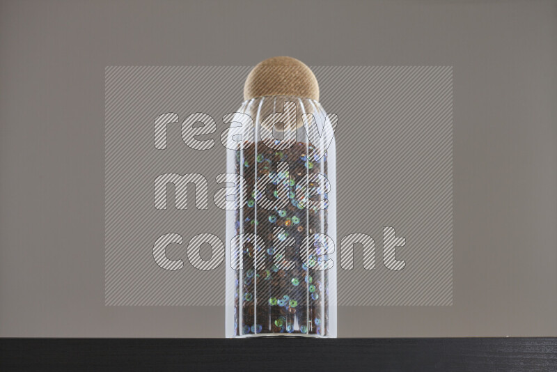 Sequins in a glass jar on black background