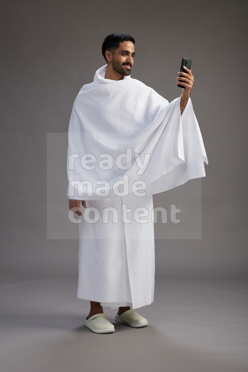 A man wearing Ehram Standing taking selfie on gray background