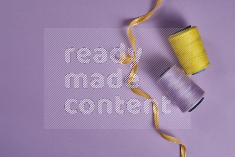 A yellow and purple collection of sewing and tailoring tools arranged on a purple background