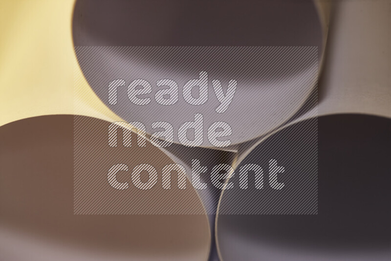 الصورة تعرض فن ورقي تجريدي بأشكال دائرية بدرجات متنوعة من اللون الرمادي والدرجات الدافئة