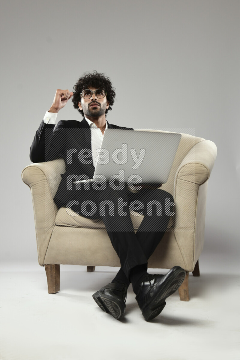 A man wearing formal sitting on a chair working on a laptop on white background