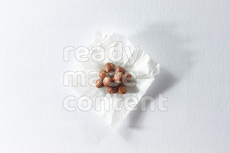 Hazelnuts on a crumpled piece of paper on a white background in different angles