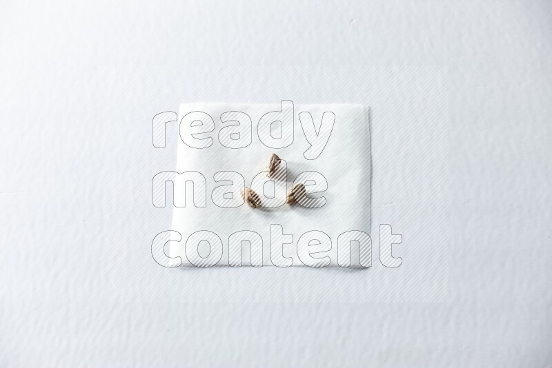 3 peeled pistachios on a piece of paper on a white background in different angles