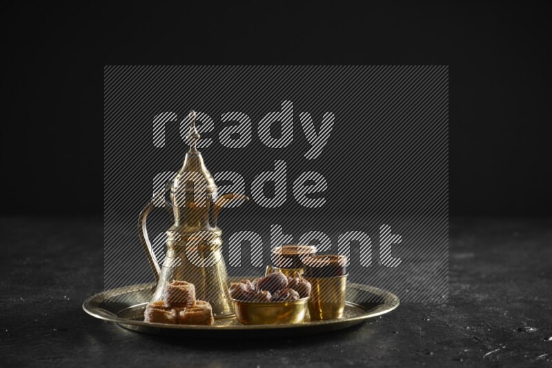 Oriental sweets with dates and a drink on a metal tray in a dark setup