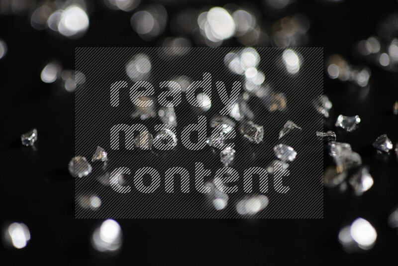 Silver shimmering fragments of glass scattered on a black background