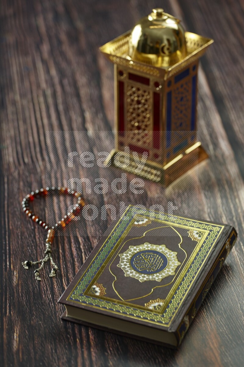 A golden lantern with different drinks, dates, nuts, prayer beads and quran on brown wooden background