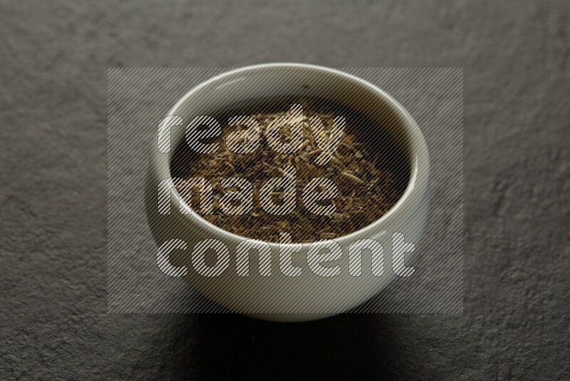 wooden round sauce bowl filled with herbs on grey textured countertop