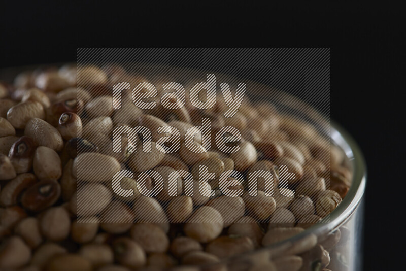 Black-eyed peas in a glass jar on black background