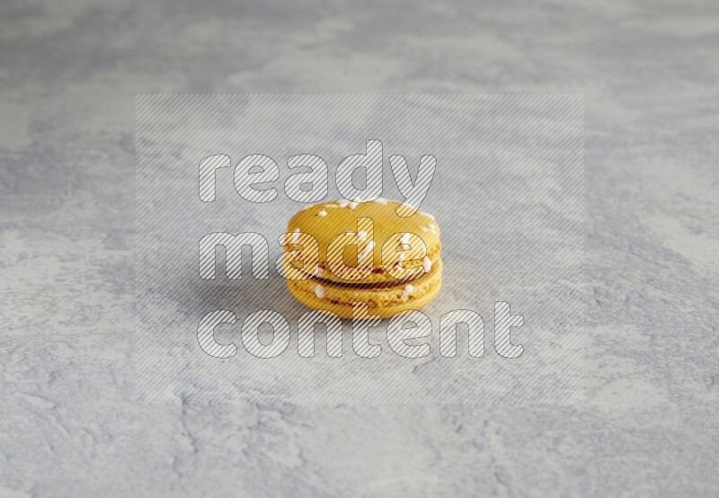 45º Shot of Yellow Piña Colada macaron on white  marble background