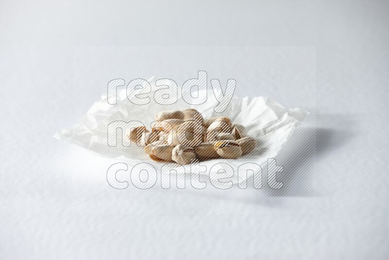 Pistachios on a crumpled piece of paper on a white background in different angles