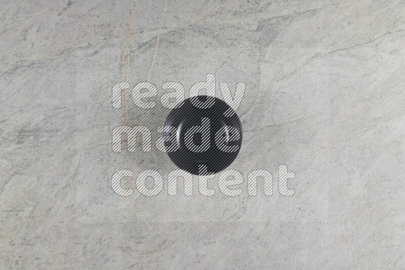 A black ceramic bowl on grey marble background