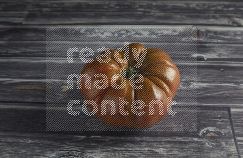 45 degree single heirloom tomato on a textured grey wooden background