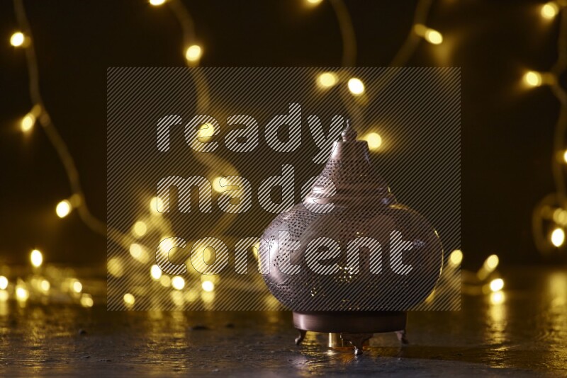 A traditional ramadan lantern surrounded by glowing fairy lights in a dark setup