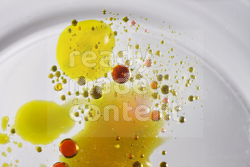 Close-ups of abstract red, green and yellow watercolor drops on oil Surface on white background