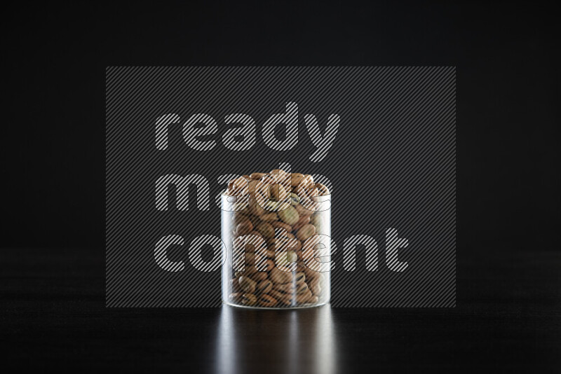Fava beans in a glass jar on black background