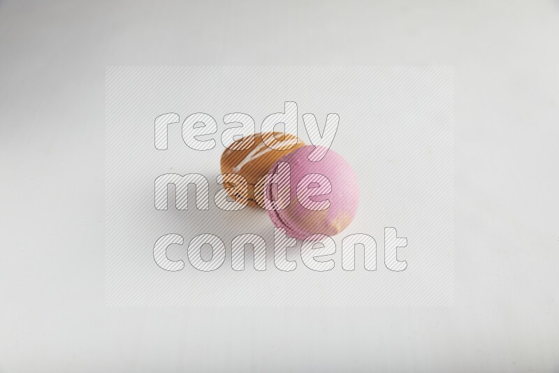 45º Shot of of two assorted Brown Irish Cream, and Purple Strawberry macarons on white background